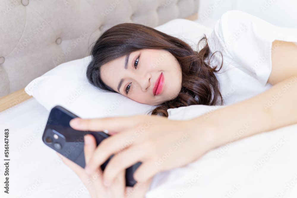 Young Asian woman using smartphone on bed