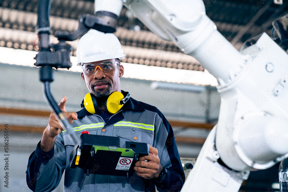 African American factory worker working with adept robotic arm in a workshop . Industry robot progra