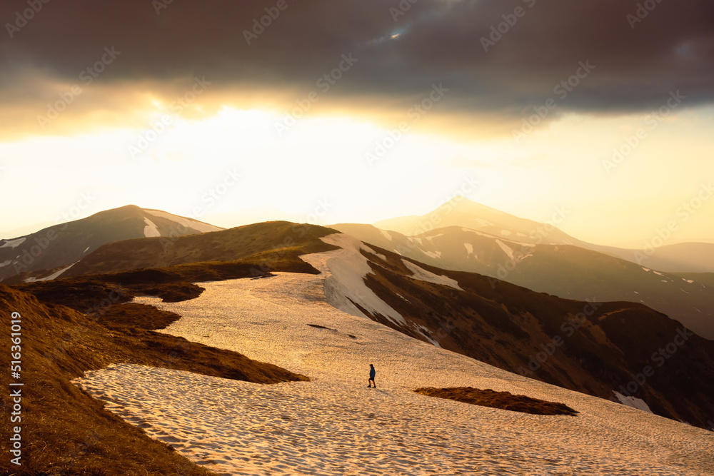 背景是长满青草的山丘和雪山。戏剧性的春天场景。风景照片。