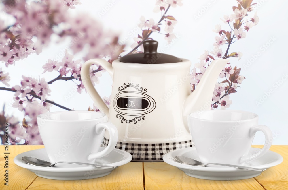 Tea concept with white tea set of cups and teapot with fresh tea on the desk