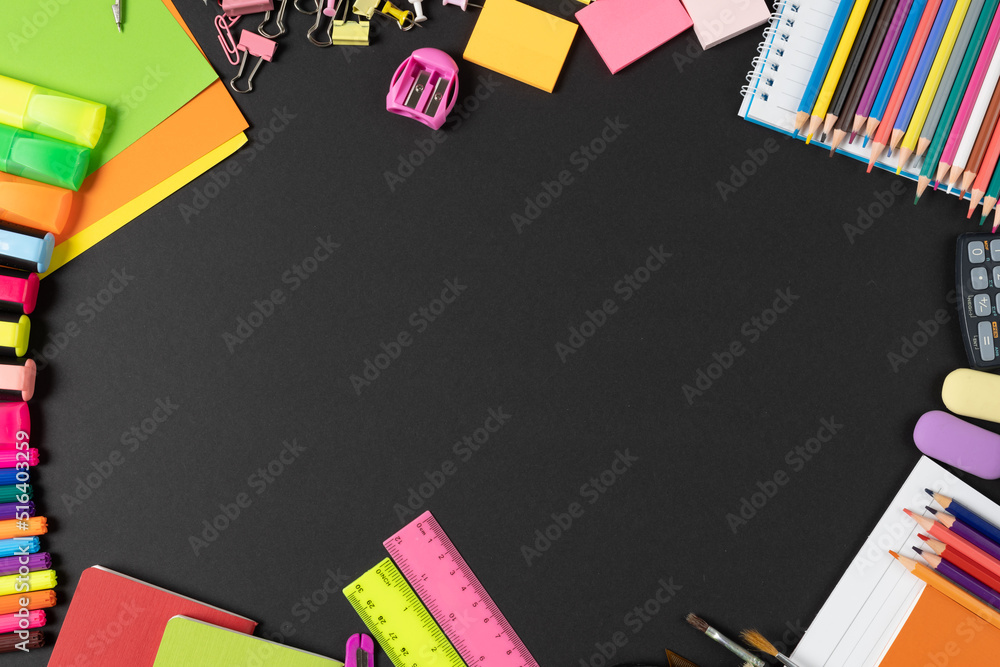 Imagine of various office supplies, pins, rulers, scissors on and pencils on black background