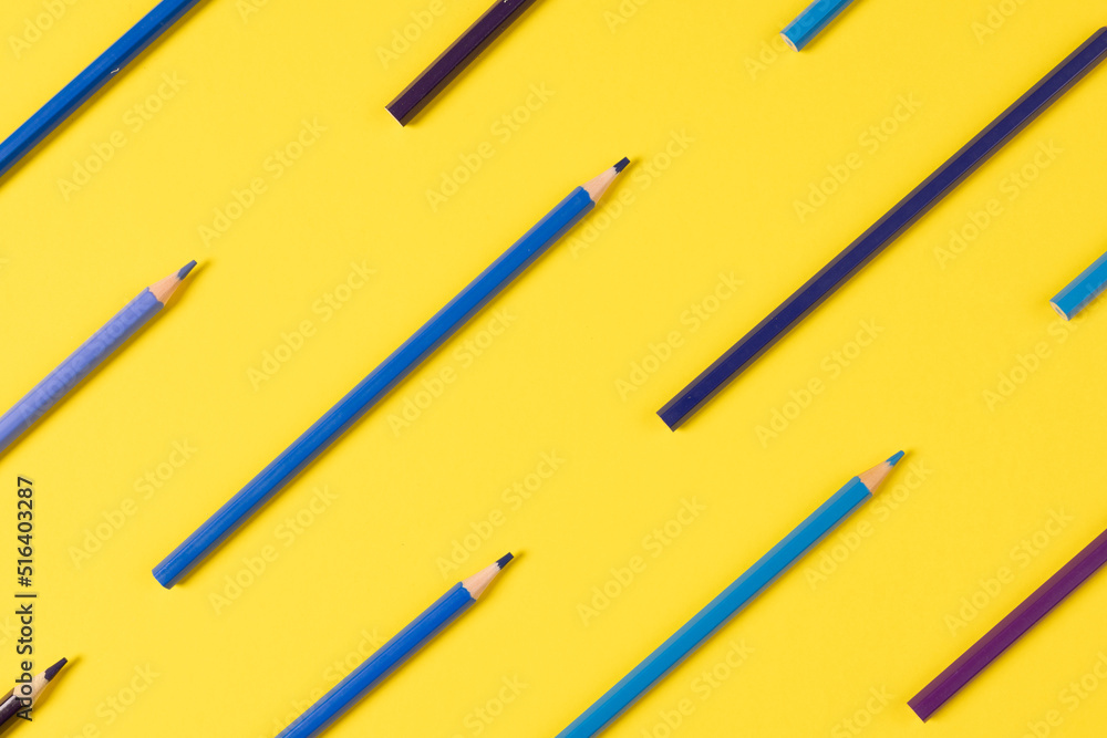 Imagine of crayons of different shades of blue on yellow background