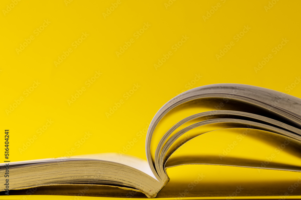 Image of open book on yellow surface with copy space