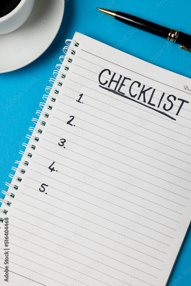 Vertical image of notebook with checklist and copy space, coffee and pen on blue surface