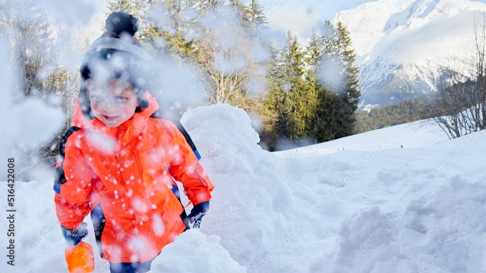 快乐的蹒跚学步的男孩在山上玩扔雪游戏