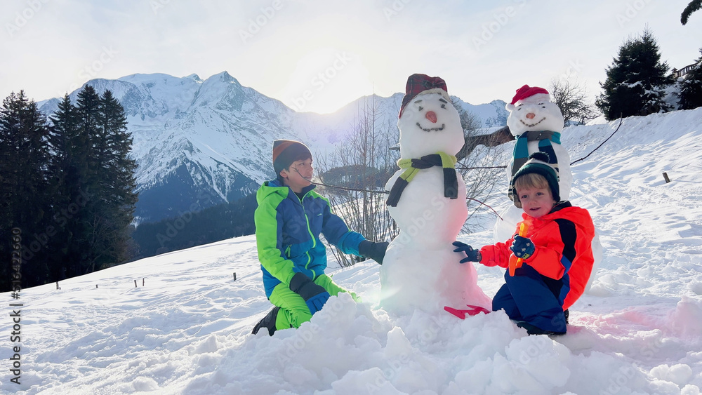 两个男孩穿着围巾一起堆雪人