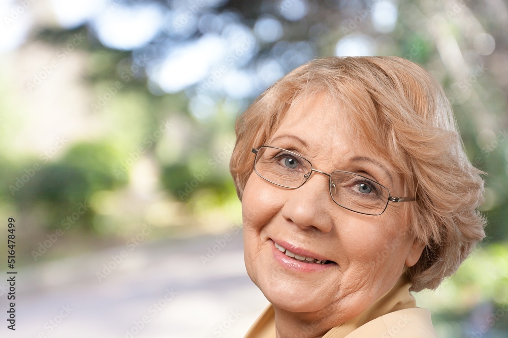 Portrait of old woman ssmile looking camera on green nature background.