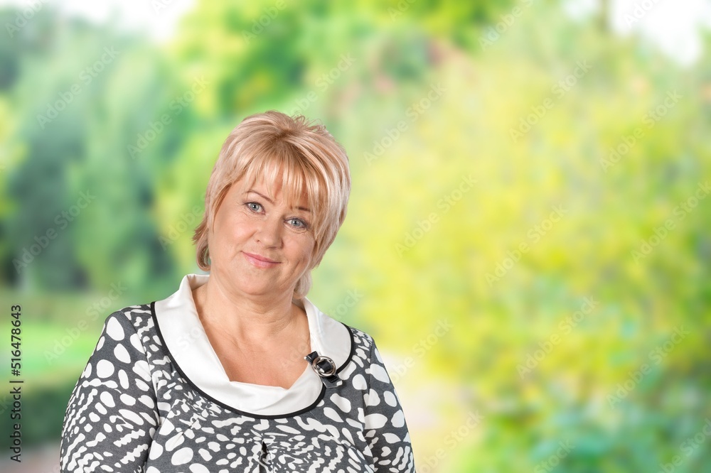 Portrait of old woman ssmile looking camera on green nature background.