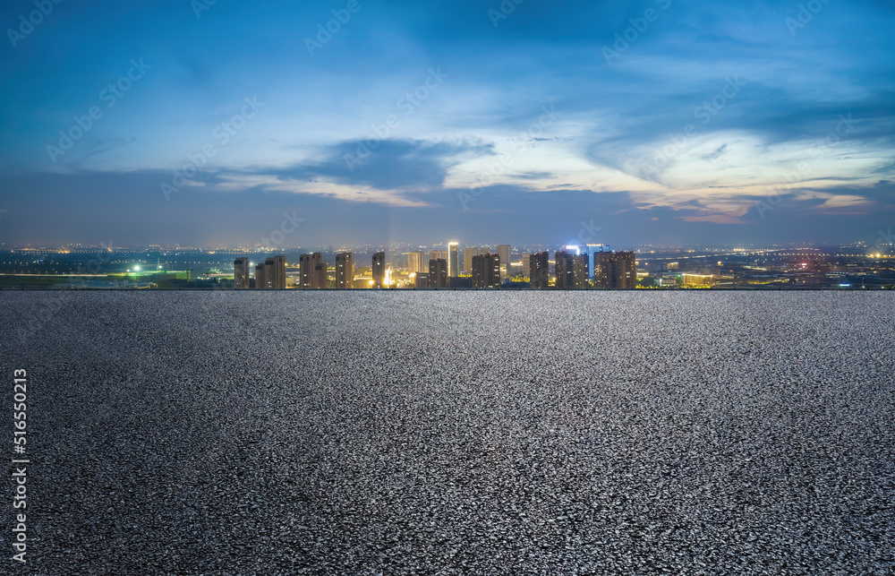 沥青路和现代城市天际线，夜晚有建筑景观。高角度视野。