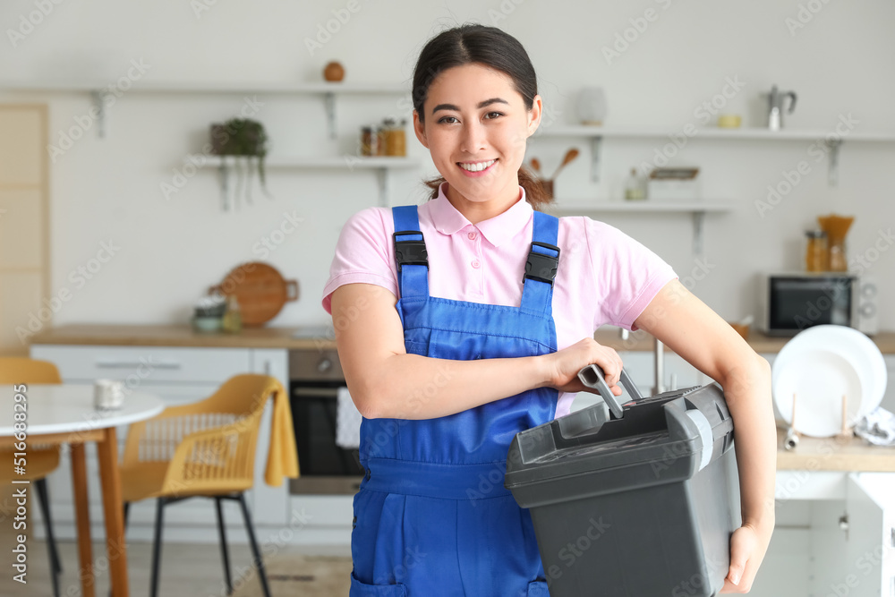 亚洲女水管工在厨房拿着装有工具的袋子