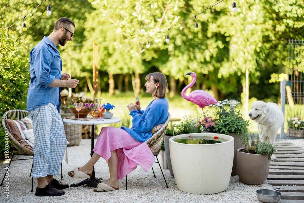 Young stylish couple hang out together with a drink at their beautiful backyard of country house on 