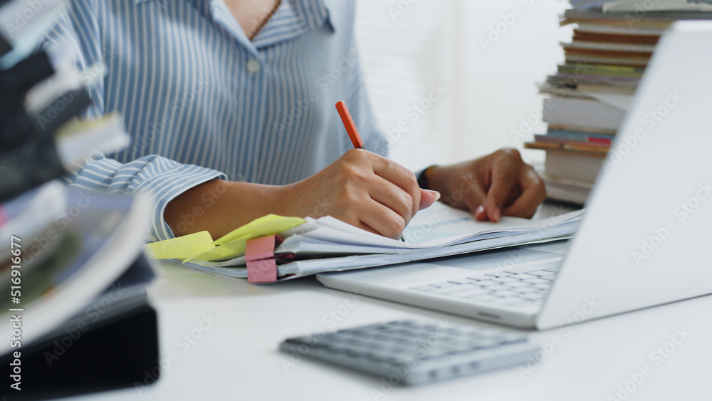 Close up of asian woman working hard with stack of document and laptop computer at office