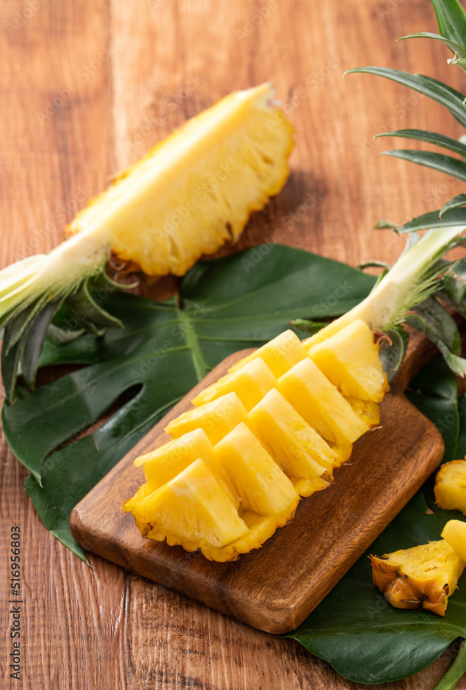 Fresh cut pineapple on a tray over dark wooden table background.