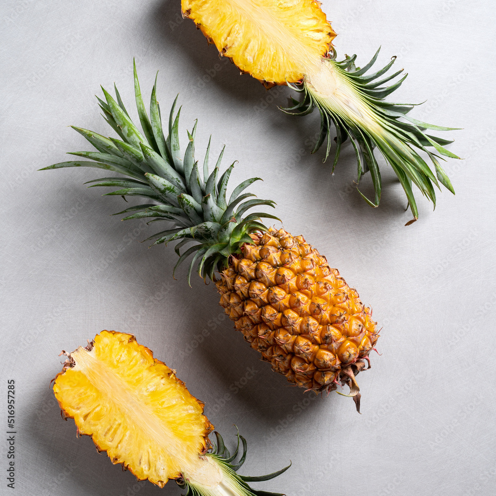 Fresh cut pineapple with tropical leaves on dark blue background.