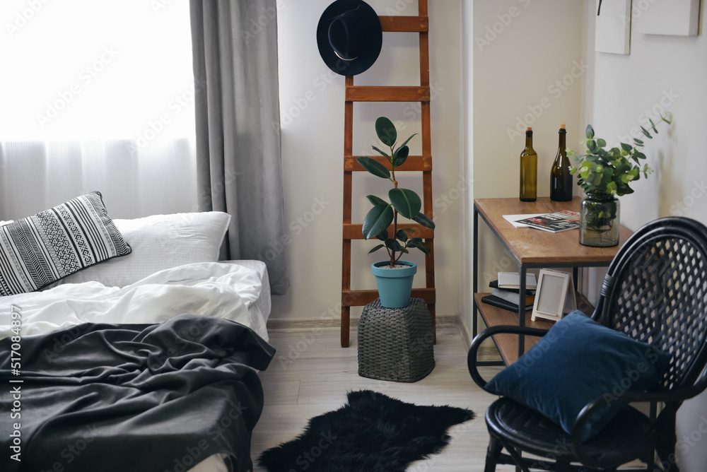 Interior of stylish bedroom with ladder and shelving unit