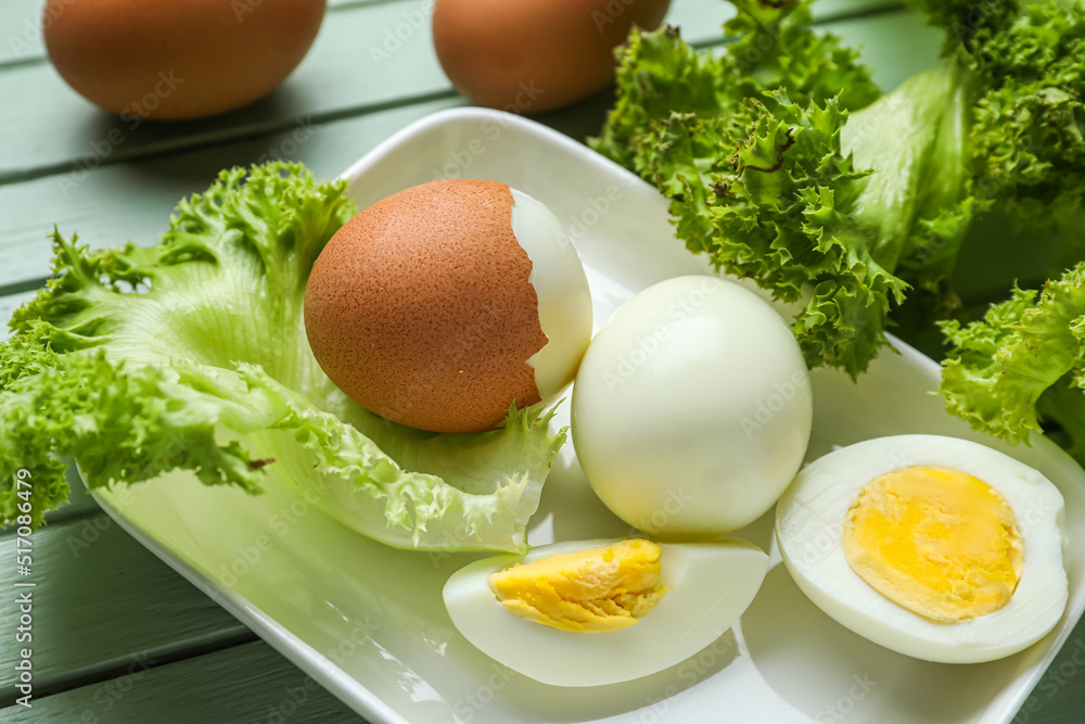 桌子上放着煮鸡蛋和生菜的盘子，特写