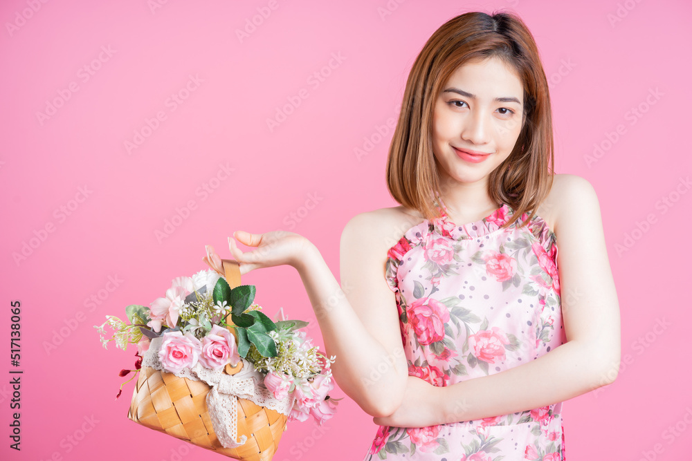 Photo of young Asian girl wearing flower dress on pink background