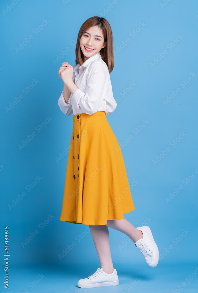 Full length photo of young Asian woman on blue background