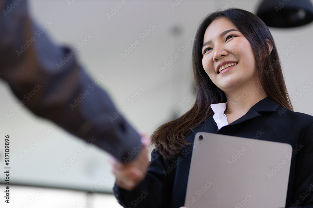 Handshake. Attractive Asian businesswoman with happy smiling face while shaking hands with coworker 