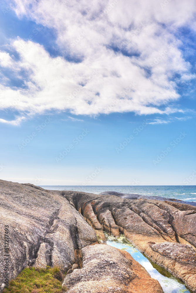 A rocky shore and a seascape view of the ocean with blue sky copy space and a mountain in the backgr