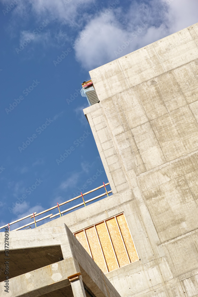 Exterior of a concrete building against a cloudy blue sky. Detail view of a tall residential or offi