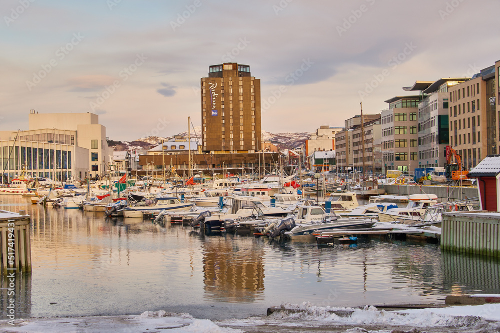 Boats and yachts docked in a harbor with the city in the background in Bodo, Norway. Sea vessels at 