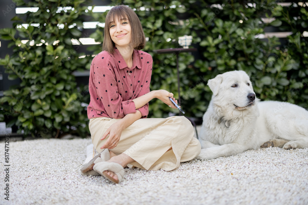 Portrait of a young woman sitting relaxed with her huge white adorable dog, spending time together a