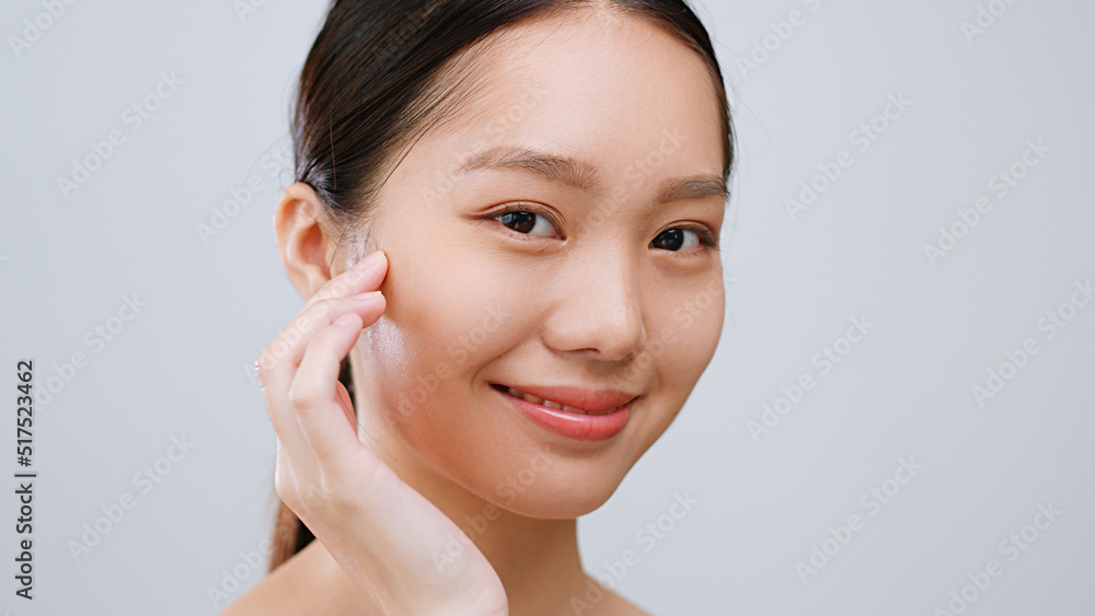 Portrait young Asian woman touching healthy facial beauty skin over grey background.