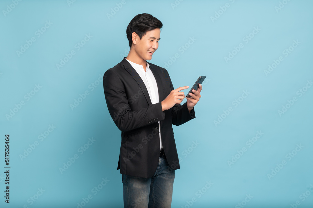 Young asian man in suit and jeans using smartphone exciteing with news on phone for smart casual bus