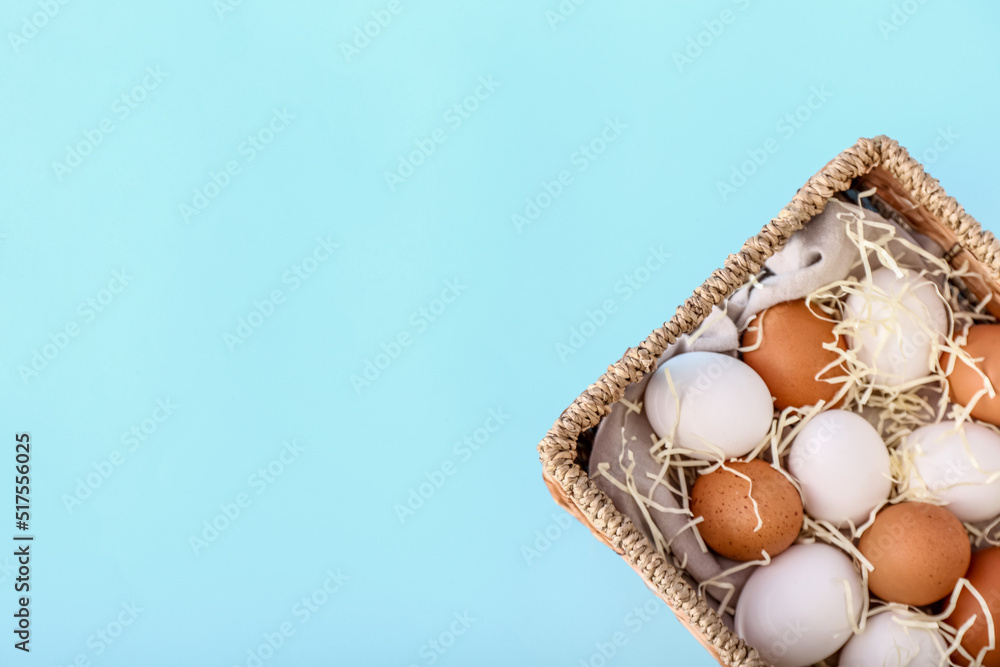 Wicker basket with different chicken eggs on color background