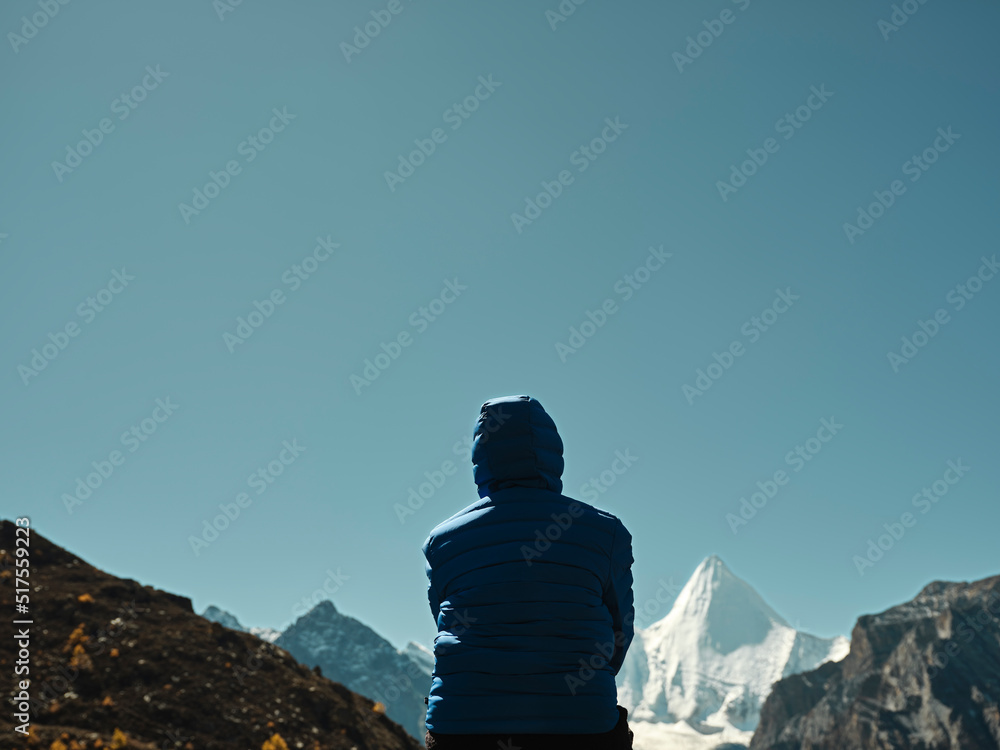 亚洲妇女在中国亚丁观看羊迈雍山（藏语为詹帕扬山）的后视图