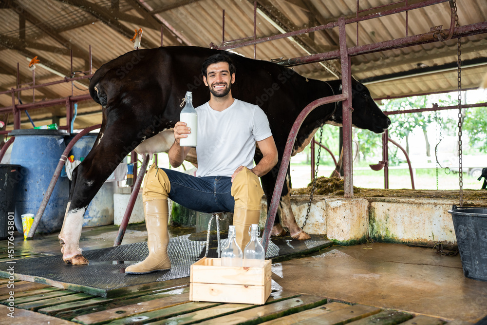 Portrait of Caucasian male dairy farmer hold bottle of milk in cowshed