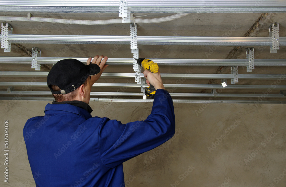 Builder installs profile metal frame for plasterboard ceilings