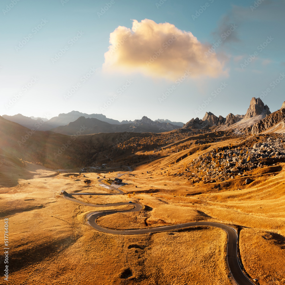 Picturesque aerial view on winding road in autumn mountain valley at sunset. The golden sunset light