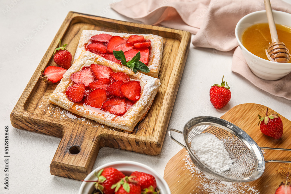 Wooden boards with strawberry puff pastry and sugar powder on light table