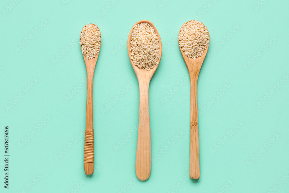 Wooden spoons with sesame seeds on green background