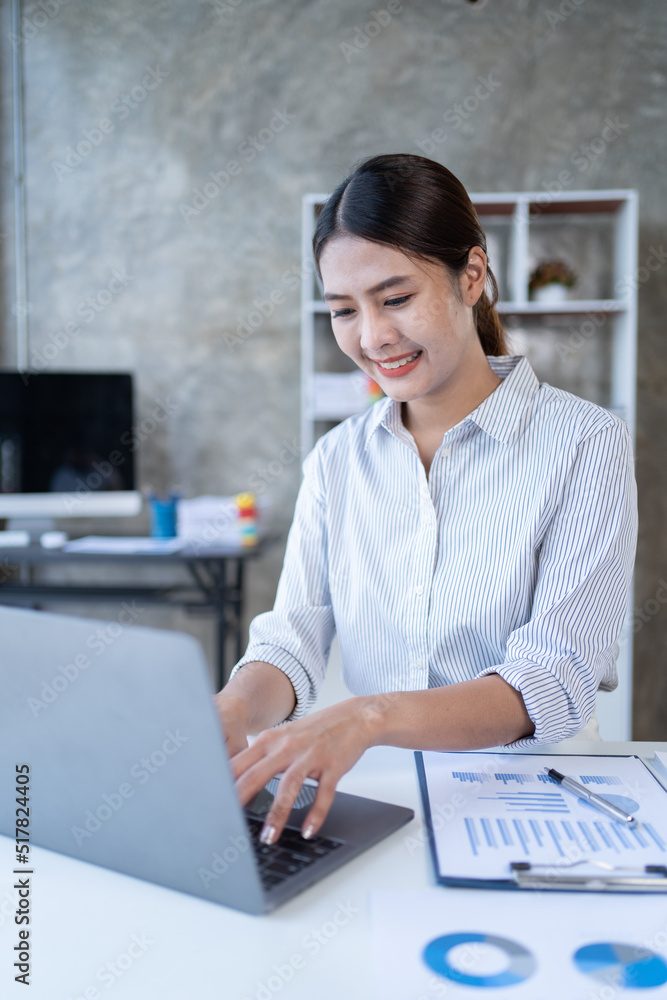 亚洲女性在办公室里用笔记本电脑工作。商业金融概念。