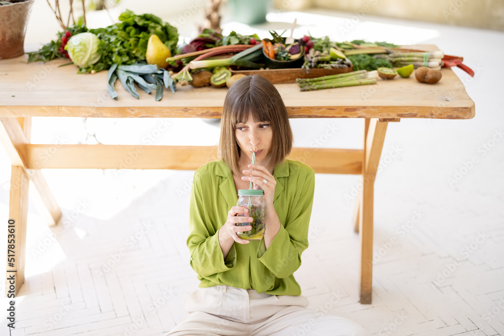 女人坐在装满新鲜食材的桌子旁喝了一些柠檬水。h的概念