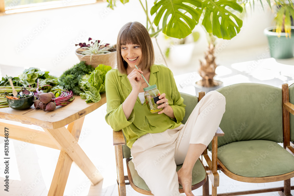 一位年轻女士坐在桌子旁边的椅子上喝柠檬水，里面有很多新鲜食品原料