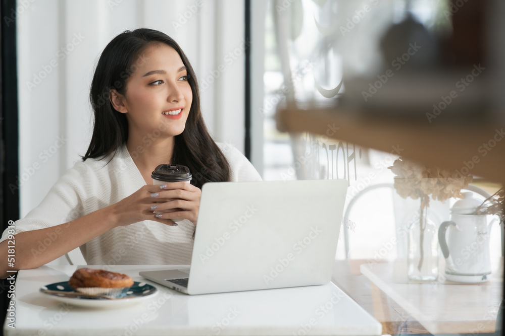 一名亚洲女子在咖啡店使用笔记本电脑，看着外面梦见什么