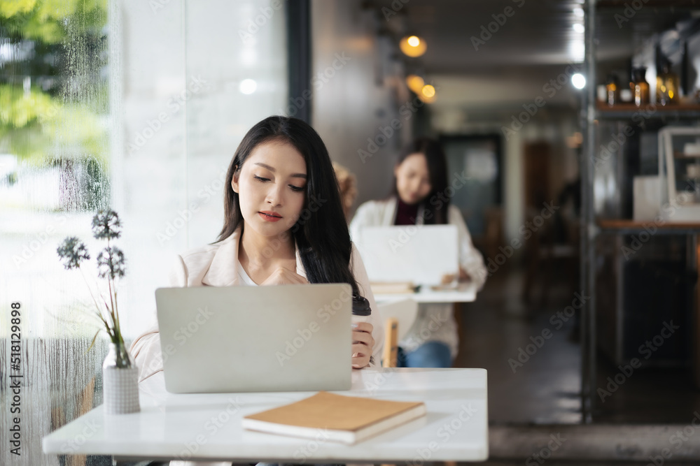 年轻的亚洲女性在咖啡店使用笔记本电脑