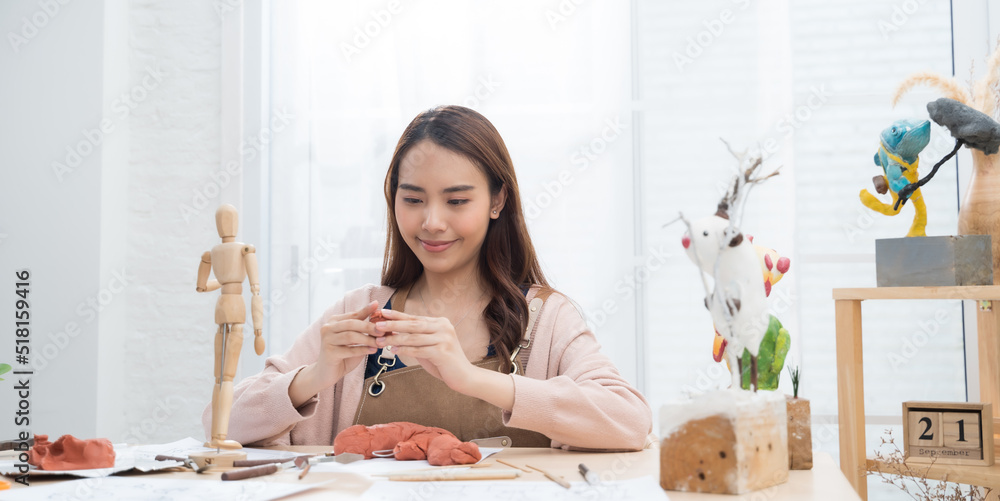 年轻的亚洲女孩在家用造型粘土制作雕塑。爱好粘土雕塑概念