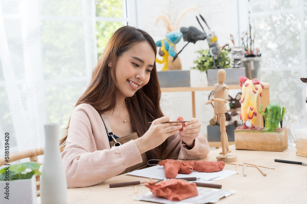 年轻的亚洲女孩在家用造型粘土制作雕塑。爱好粘土雕塑概念