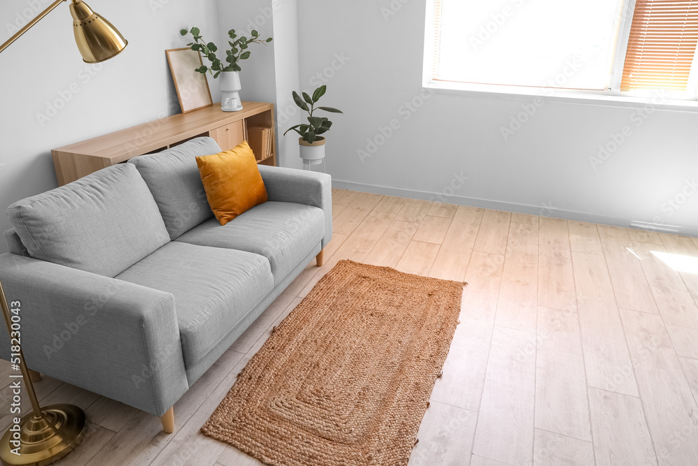 Interior of light living room with grey sofa and shelving unit