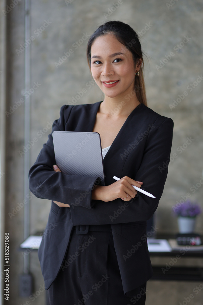 一位美丽的亚洲商业女性站在办公室里看着相机的肖像。