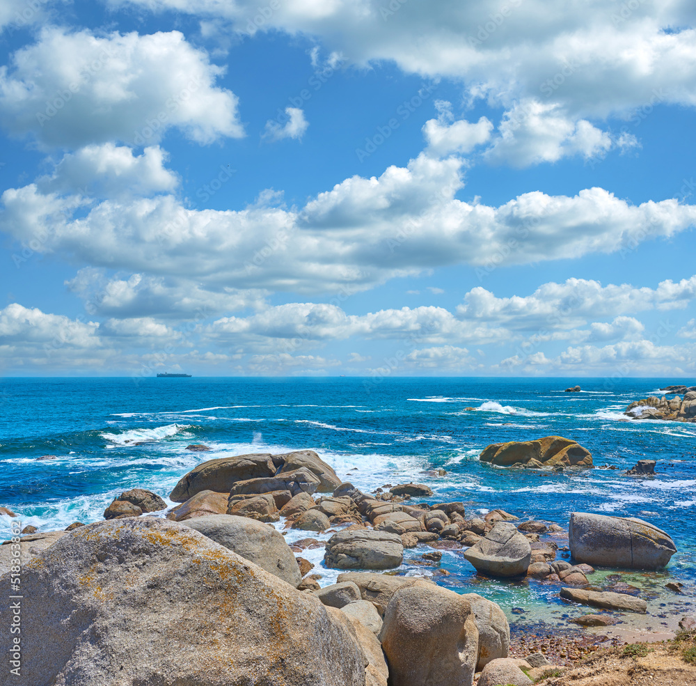 Rocks in the ocean under cloudy blue sky background with copy space. Beautiful landscape of beach wa