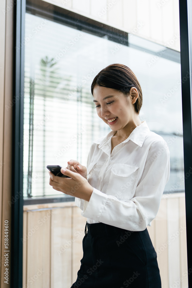 Asian businesswoman in formal suit in office happy and cheerful during using smartphone and working.