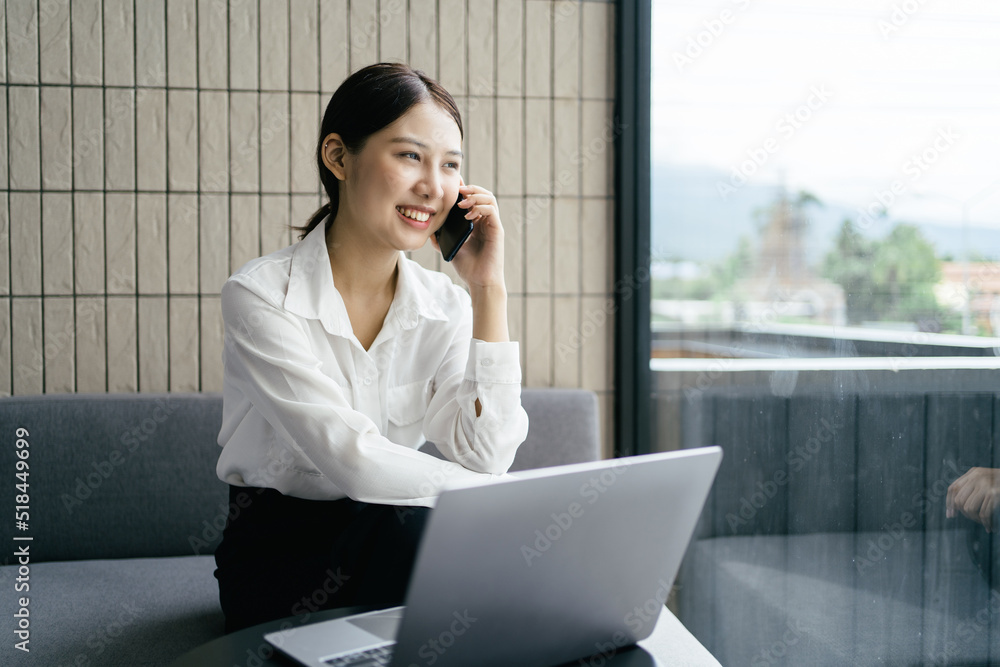 Asian businesswoman in formal suit in office happy and cheerful during using smartphone and working.