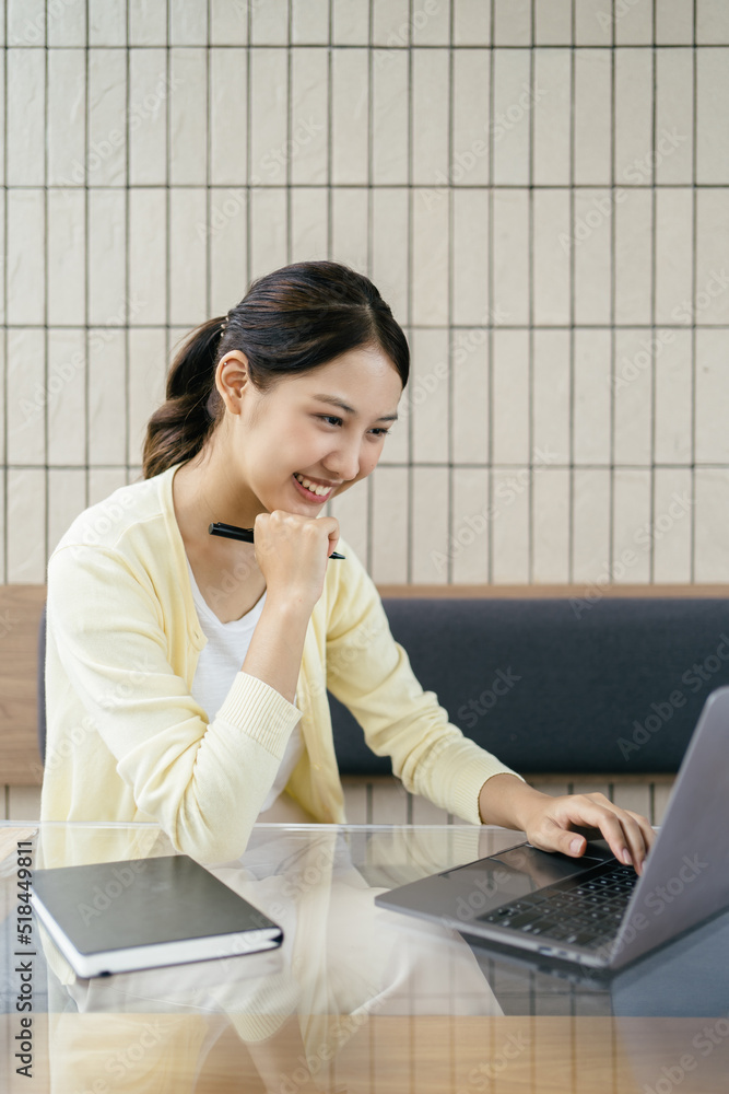 有魅力的亚洲女人在客厅里用笔记本电脑。