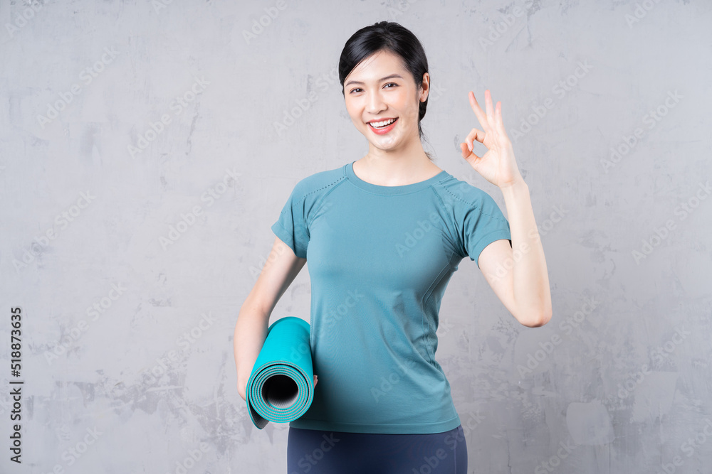 image of young Asian woman holding yoga carpet